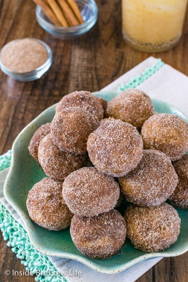A green plate filled with apple cider donut holes rolled in cinnamon sugar.