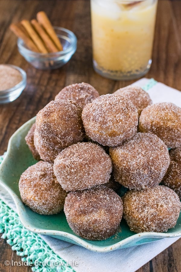 A green plate piled with cinnamon sugar apple donuts.