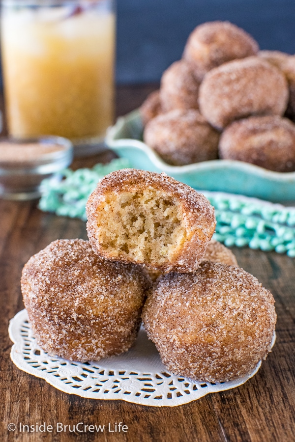 A stack of three cinnamon sugar apple donut holes with a bite taken out of the top one.