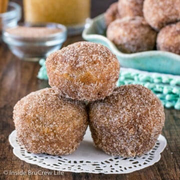 Three apple donut holes stacked on a white paper.