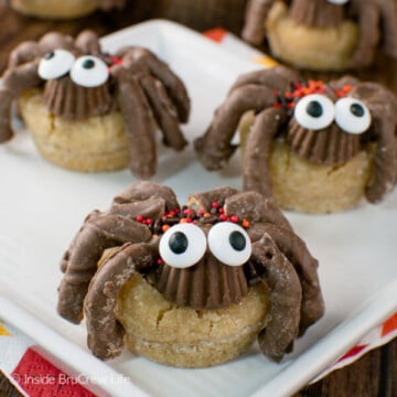A white plate with three peanut butter cup spider cookies with candy eyes on it