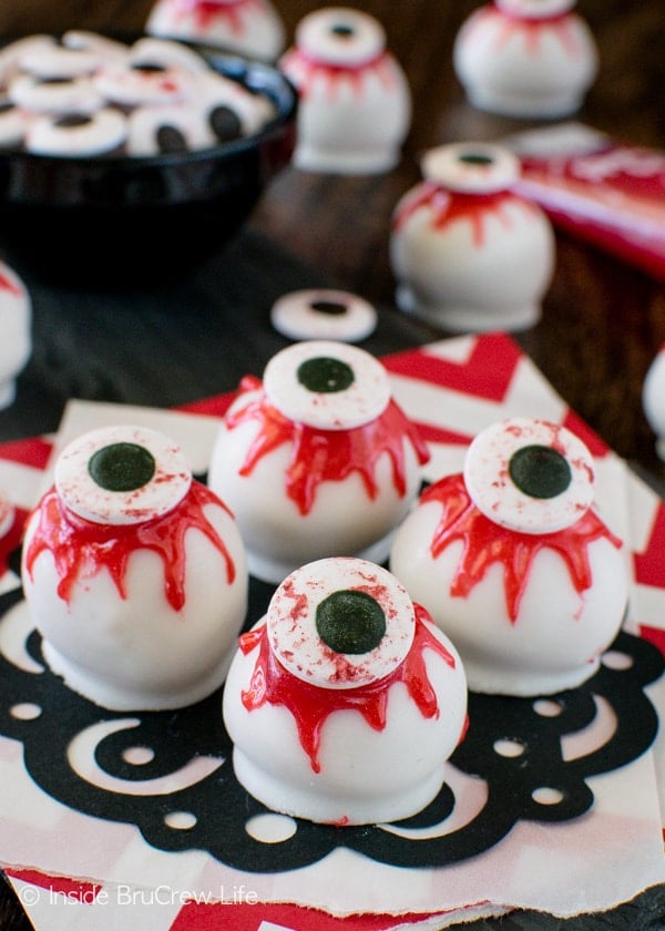 A black doily with four peanut butter zombie eyeballs on it and a bowl of candy eyes behind them.