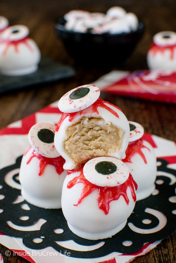 A black doily with peanut butter zombie eyeballs stacked on it with a bite taken out of the top one.