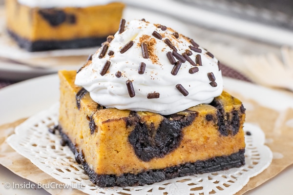A white plate with a square of pumpkin swirled brownies topped with Cool Whip and sprinkles.