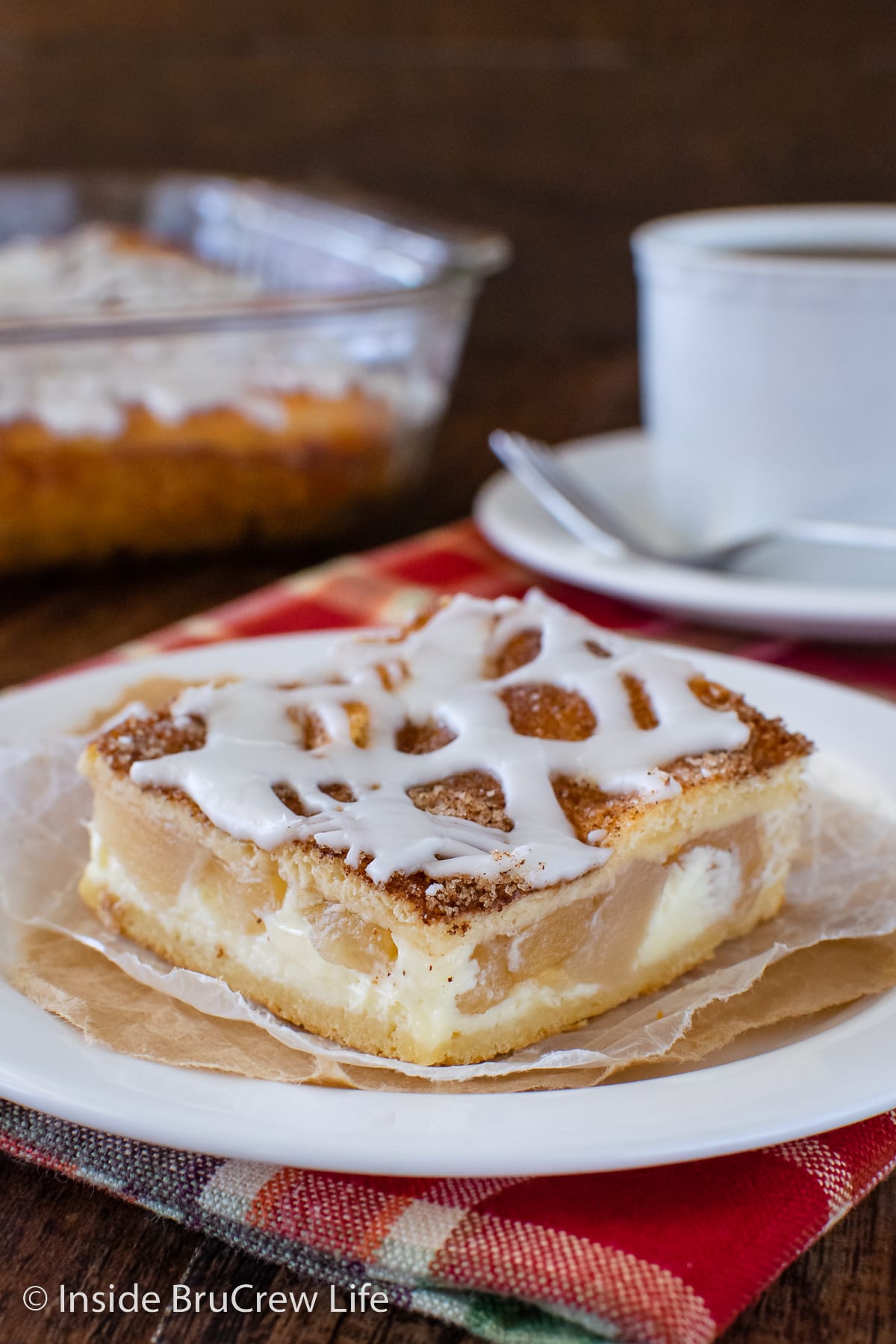 A slice of apple cream cheese dessert on a white plate.