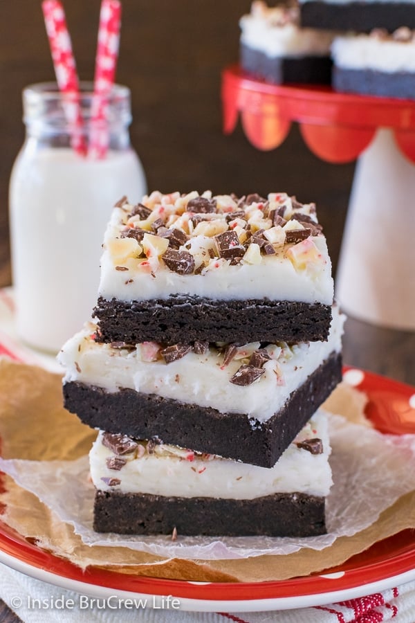 Three frosted chocolate peppermint sugar cookie bars stacked on top of each other on a red plate
