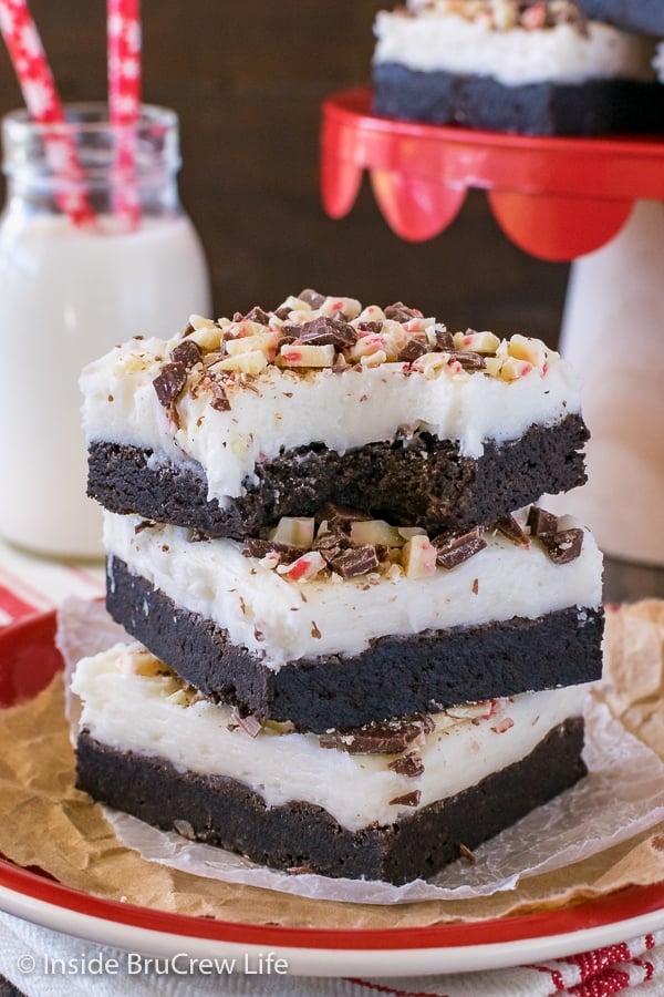 Three chocolate peppermint sugar cookie bars stacked up on a red plate with a bite out of the top cookie bar