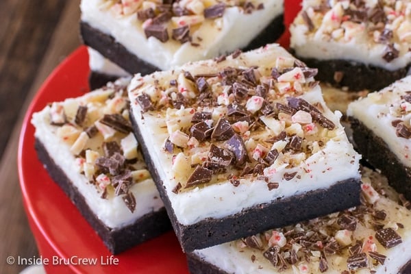 A red cake plate with frosted chocolate peppermint sugar cookie bars stacked on it