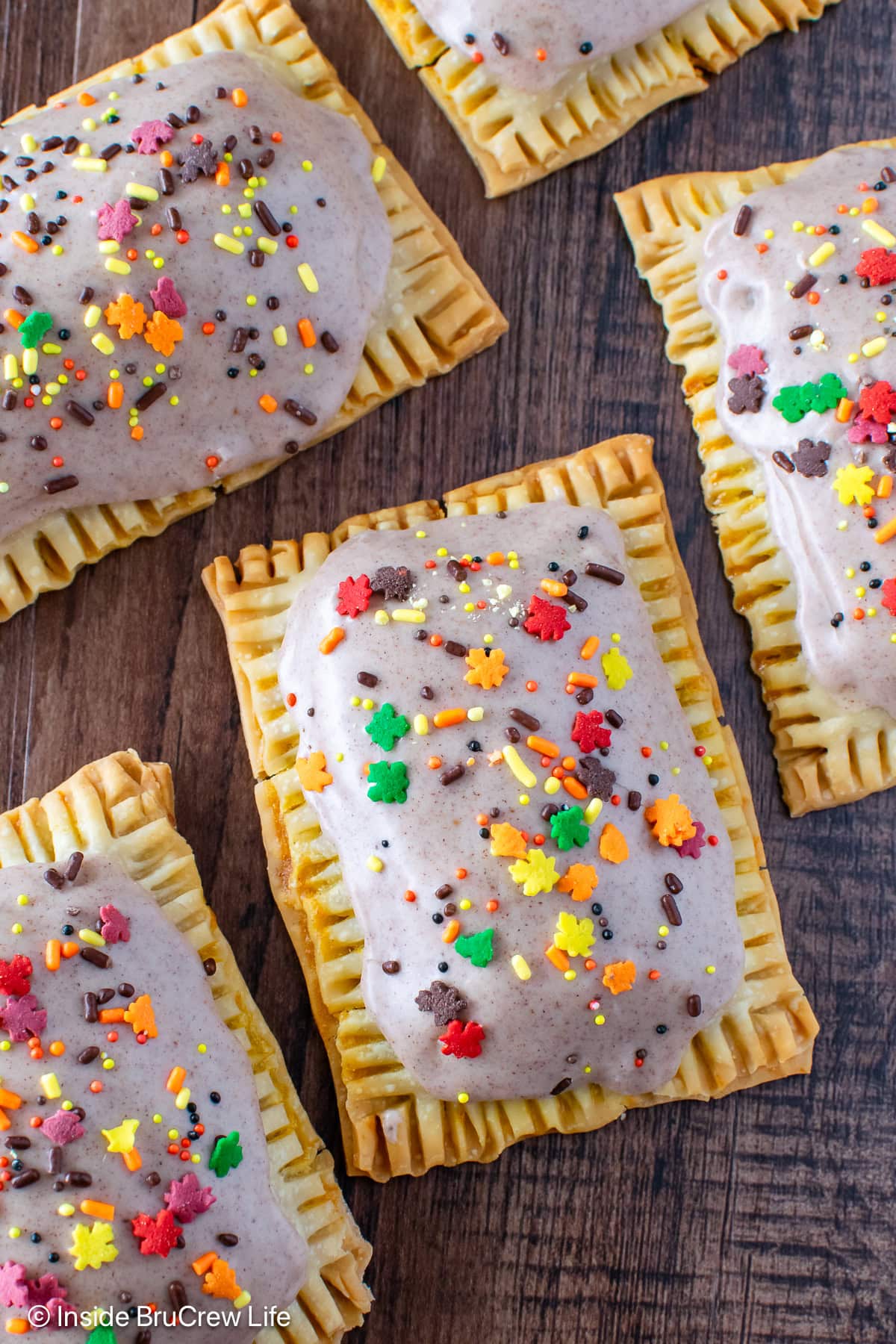 Glazed pie crust tarts with sprinkles on a wood board.