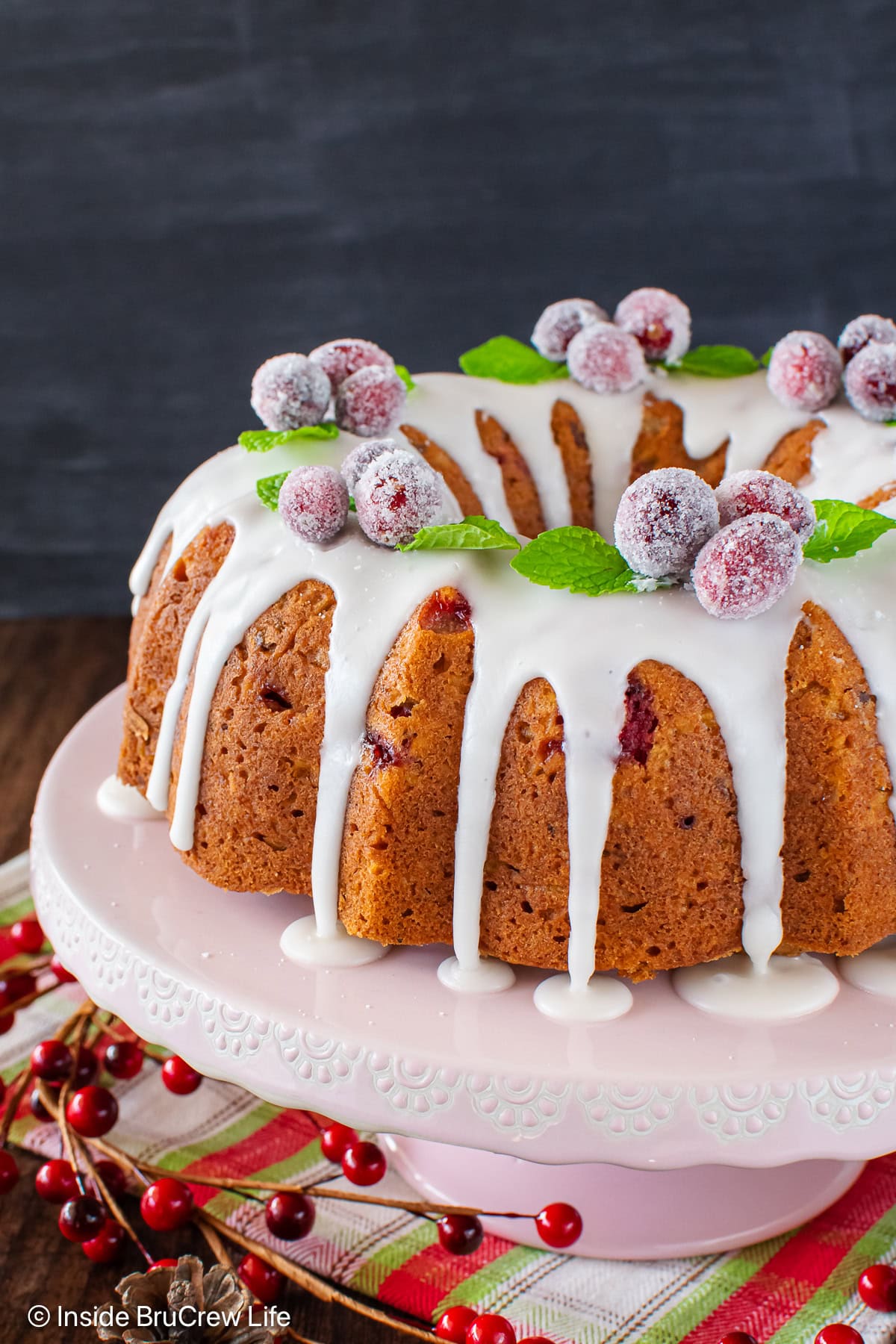 The side of a bundt cake with a glaze dripping down the side.