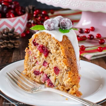 A slice of apple cranberry cake on a white plate.