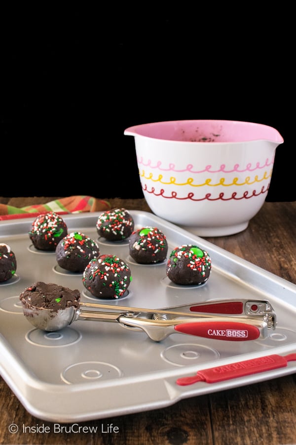 A pan of uncooked Chocolate Mint Pudding Cookie balls with a cookie scooper.