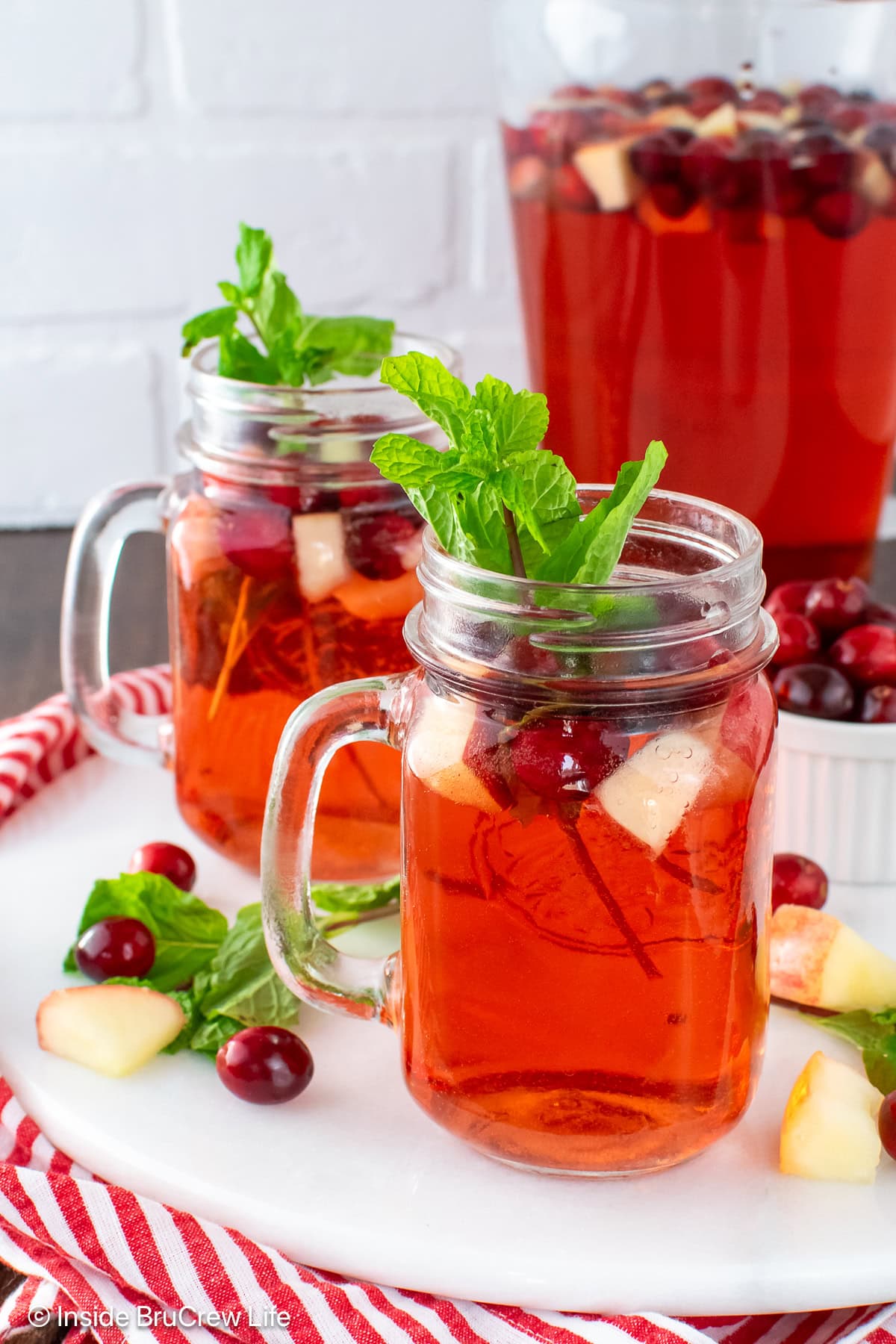 Clear glasses and a pitcher of red Christmas punch.