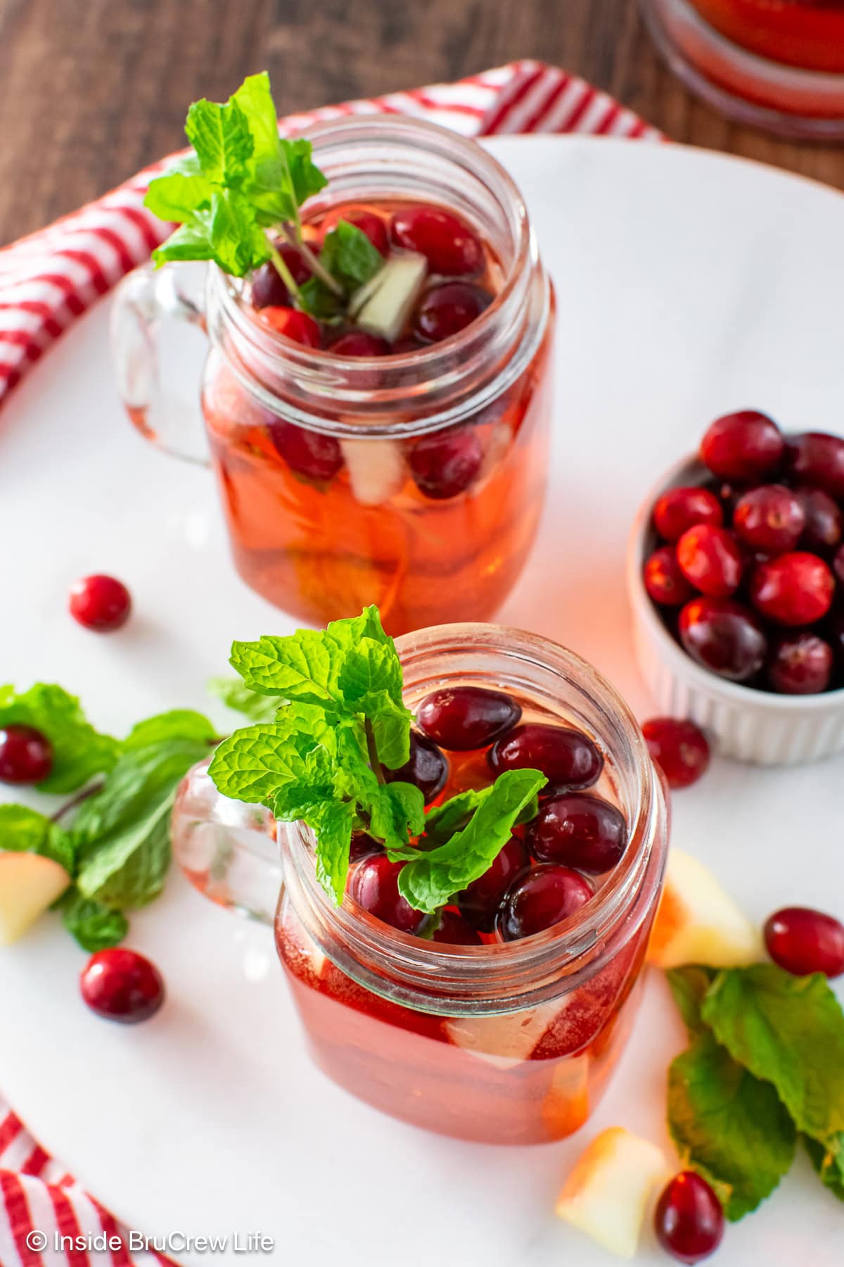 Two glass cups filled with cranberry punch and floating fruit.