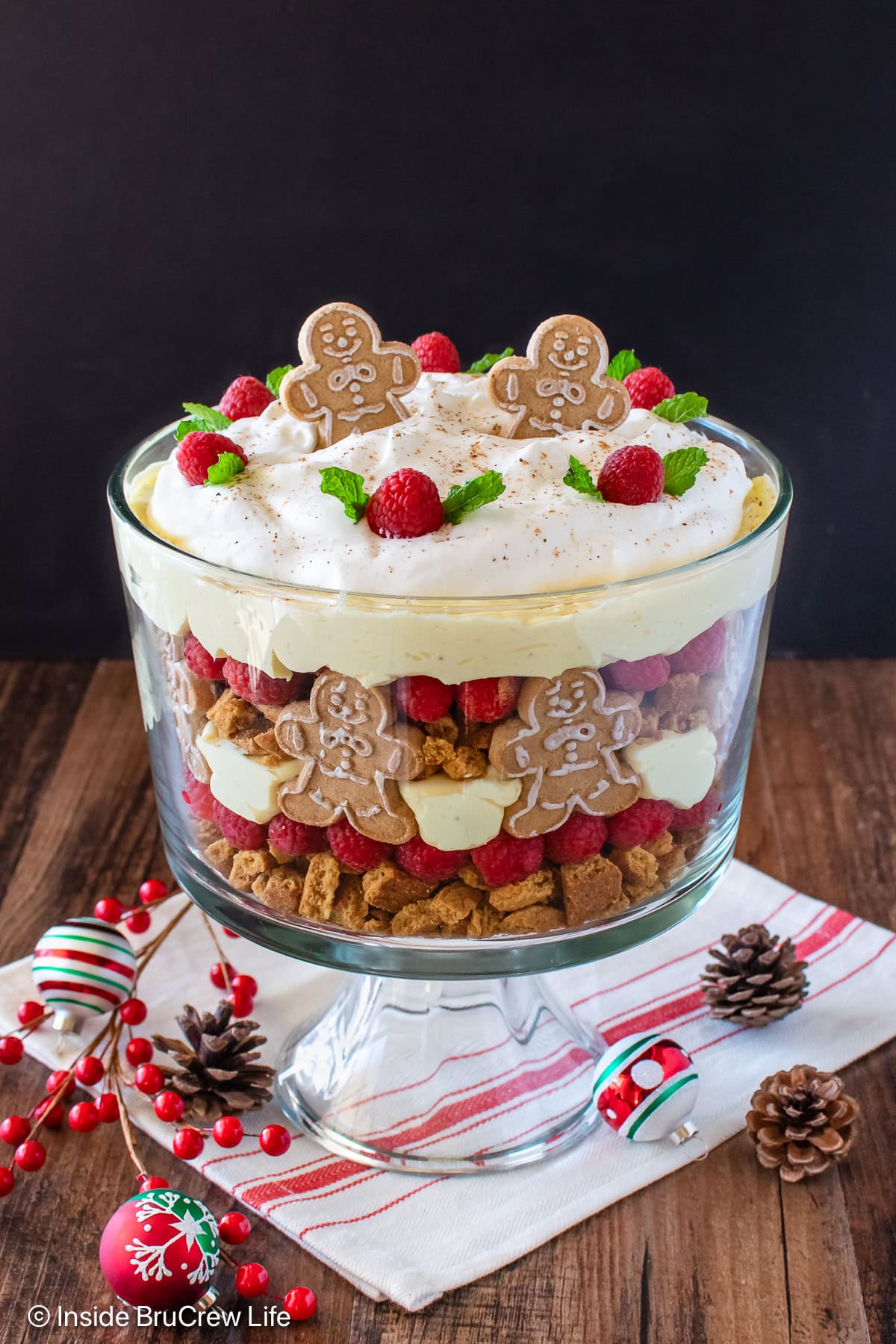 Layers of pudding, cookies, and raspberries in a clear trifle dish.