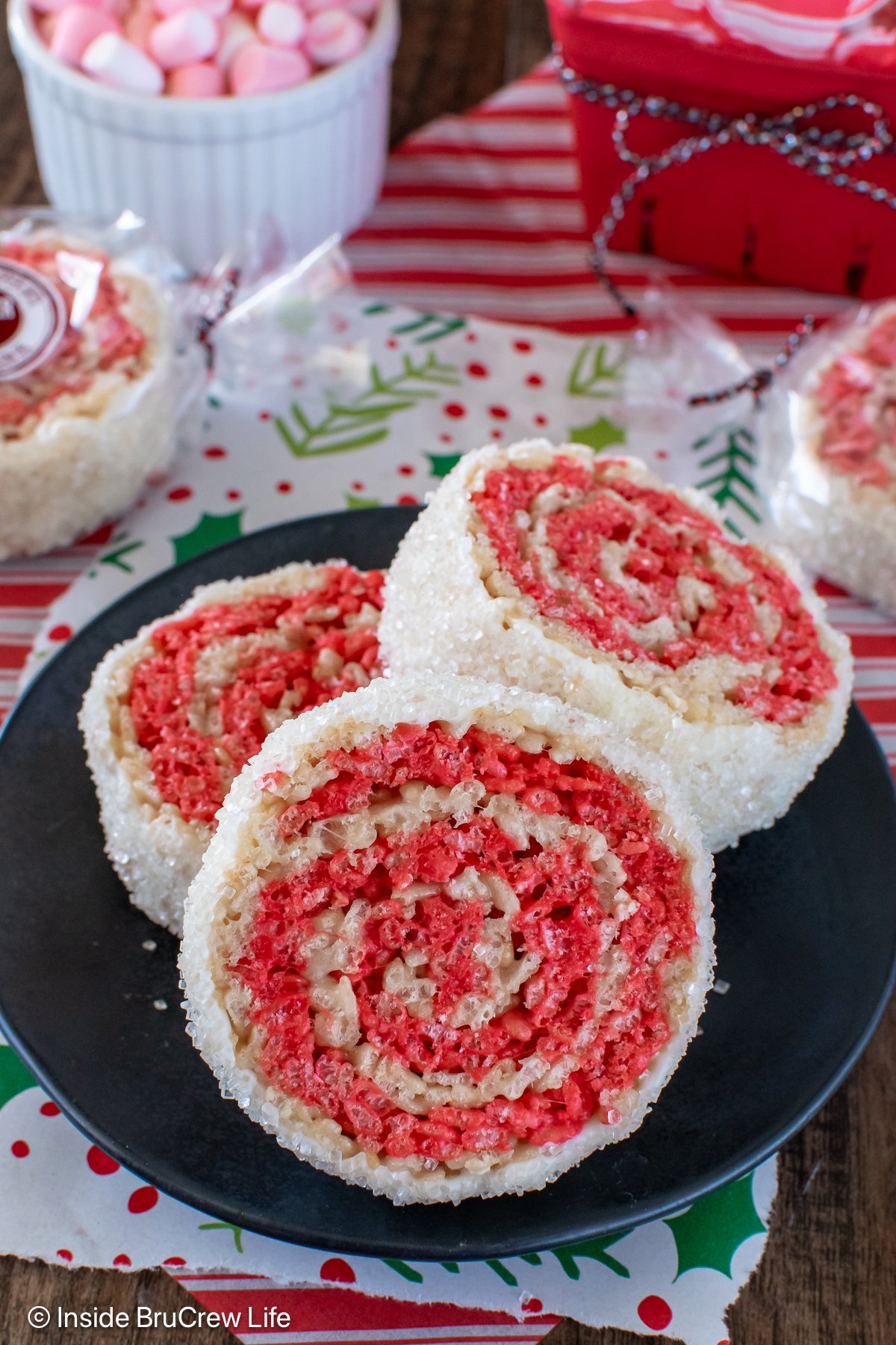 Three peppermint rice krispie treat pinwheels on a black plate.