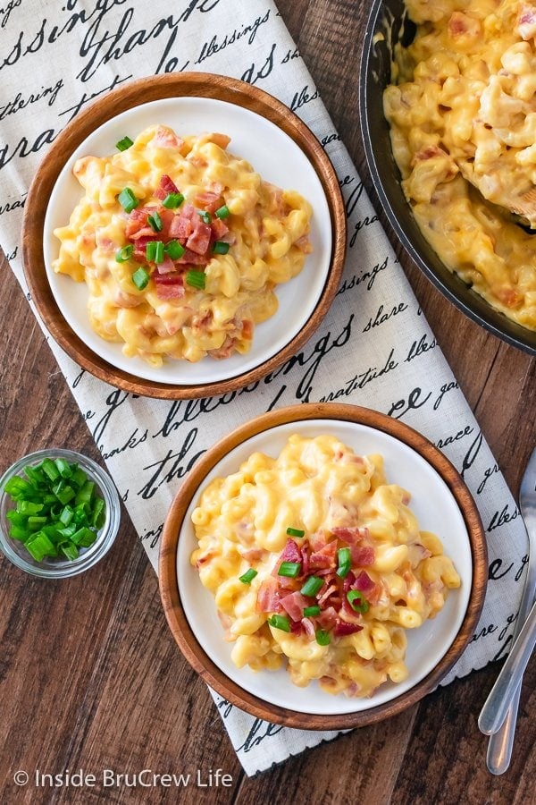 Two white plates with large servings of cheesy mac and cheese and bacon.