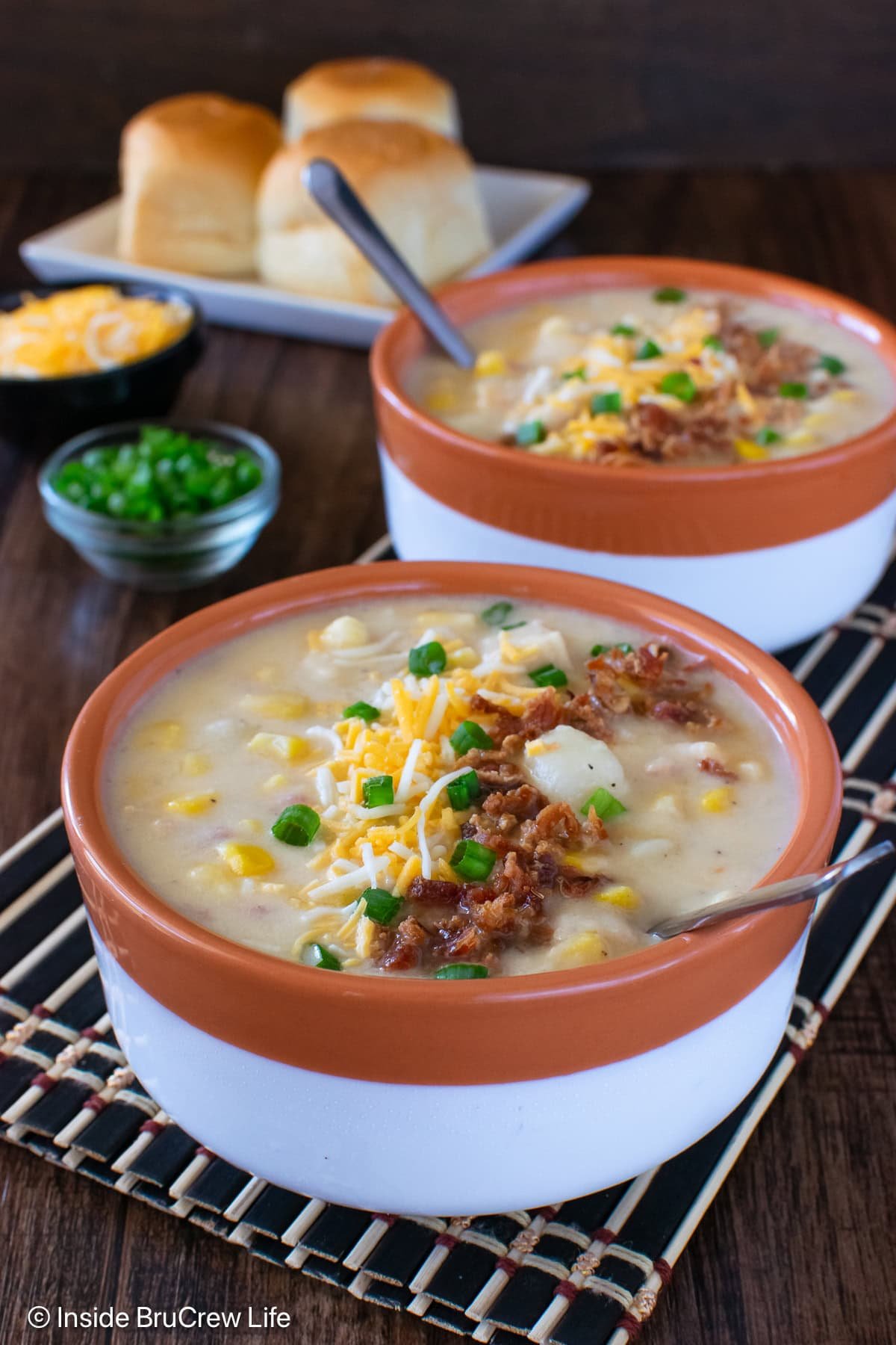 Two bowls of chicken potato corn chowder with toppings.