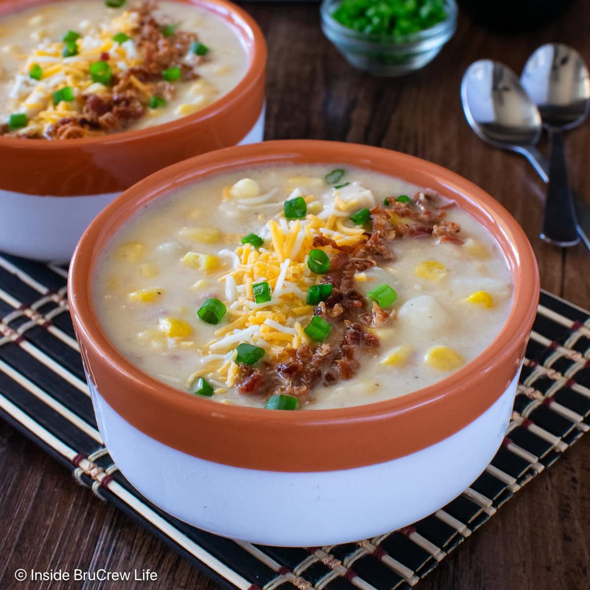 A bowl of chicken chowder topped with cheese and bacon.