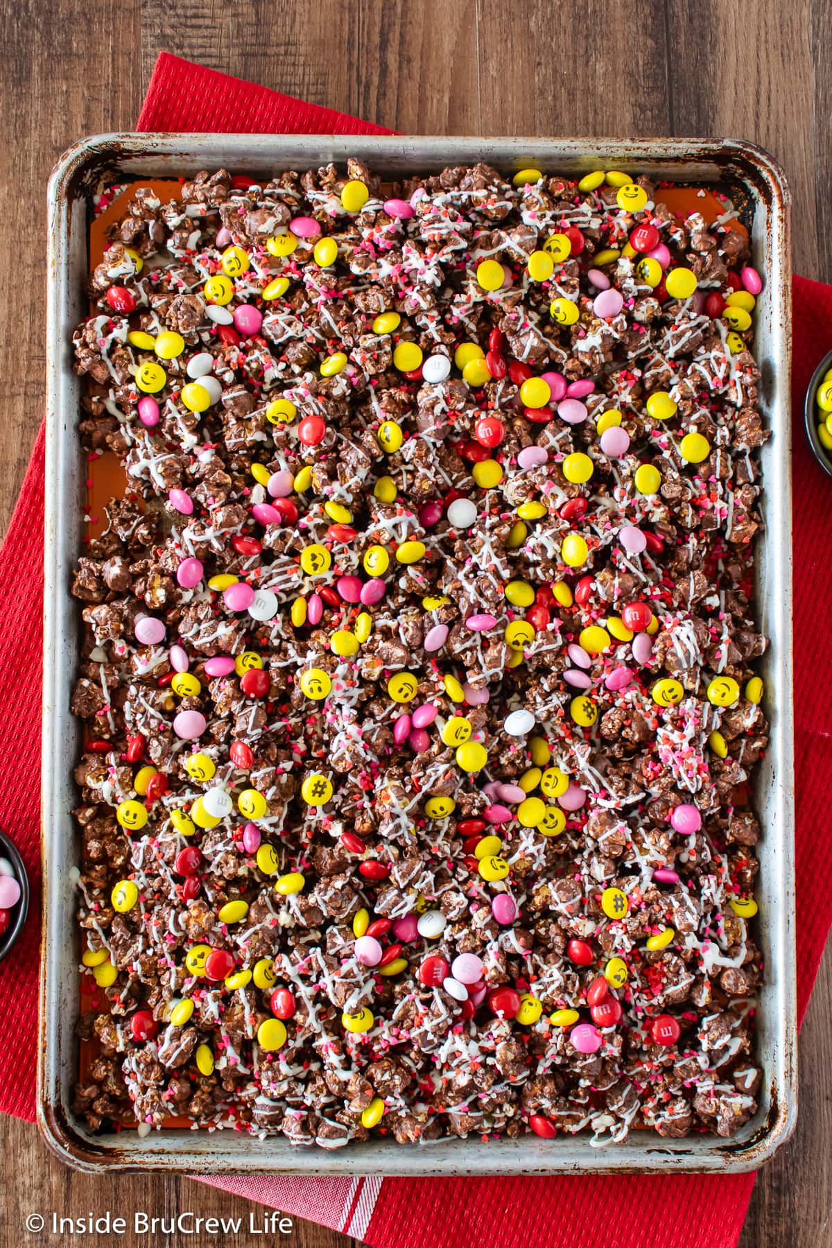 A baking sheet filled with chocolate covered popcorn and candies.
