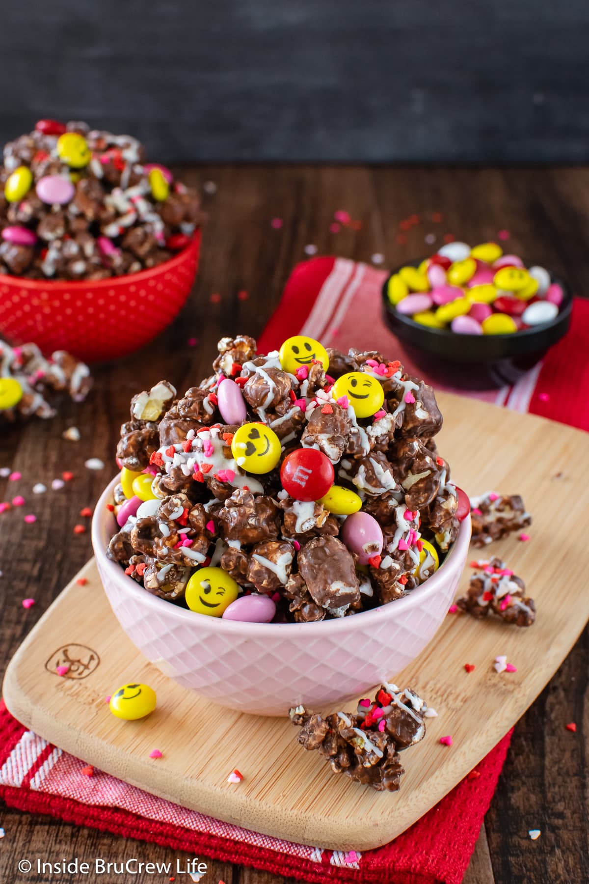 A pink bowl of chocolate popcorn and candy.