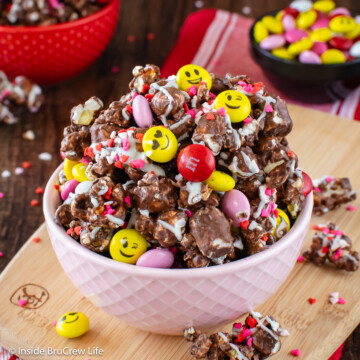 A pink bowl of chocolate popcorn and candy.