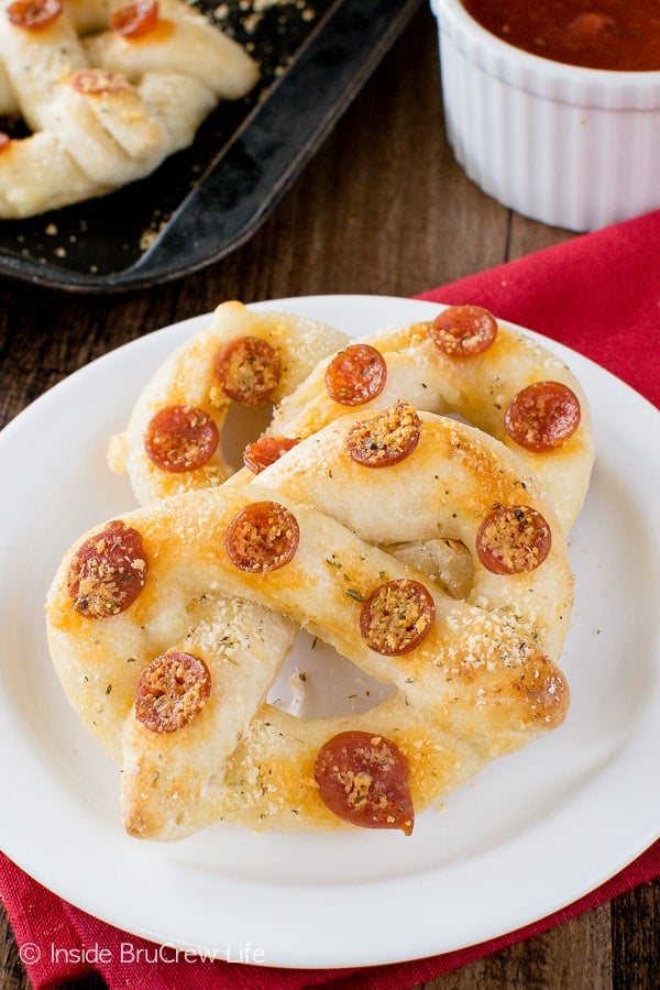2 pepperoni cheese pretzels on a white plate.