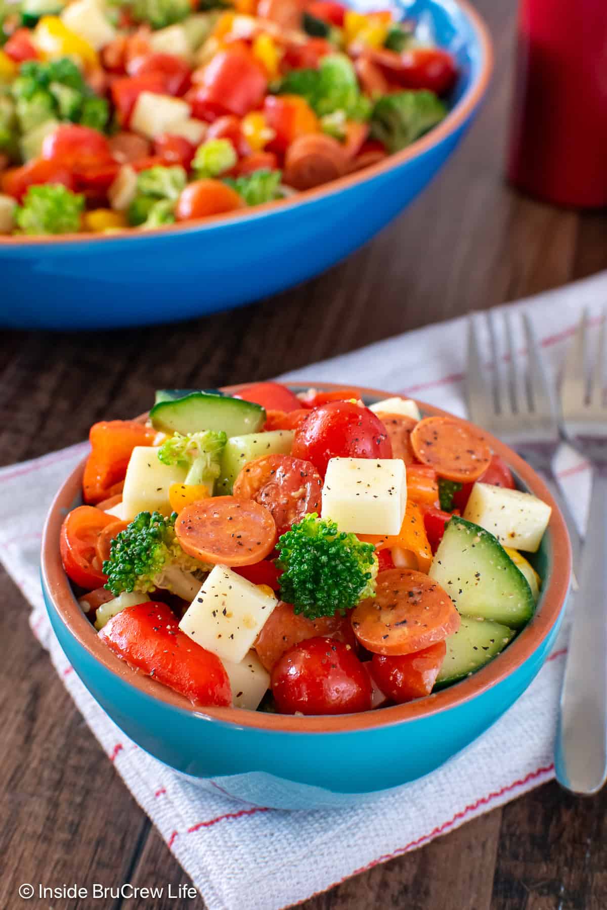 A small bowl filled with an Italian veggie salad with more behind it.