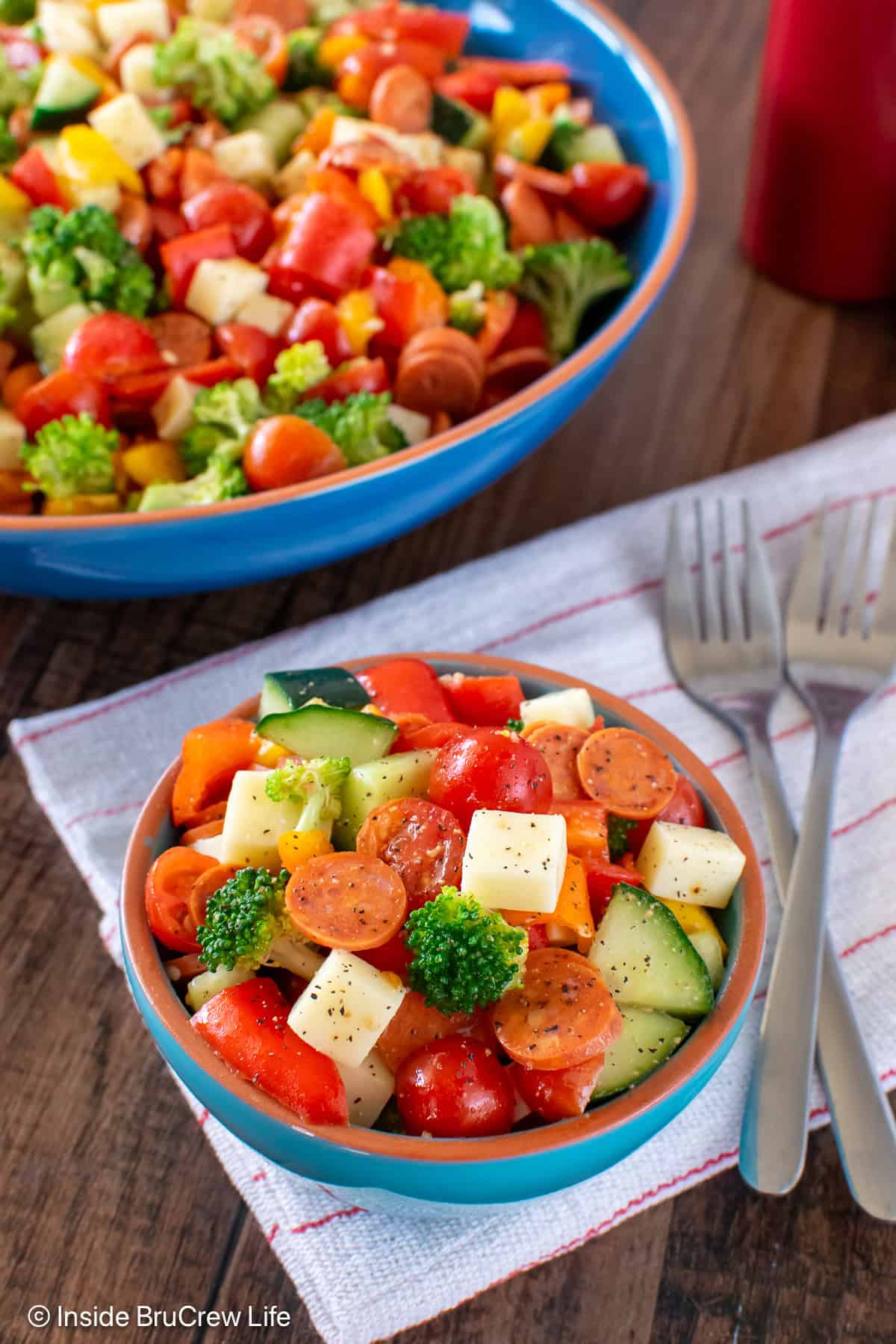 A large and a small bowl filled with a chopped veggie salad.