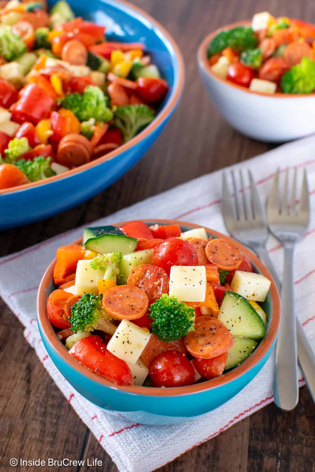 A small bowl filled with an Italian veggie salad with more behind it.