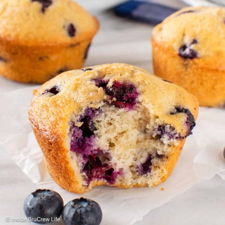 A sour cream blueberry muffin with a bite out of the front of it.
