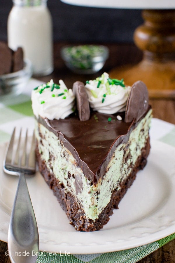 A slice of thin mint cookie cheesecake with a brownie crust on a white plate.