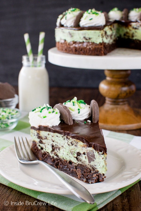 A white plate with a slice of no bake mint cheesecake with a brownie crust on it.