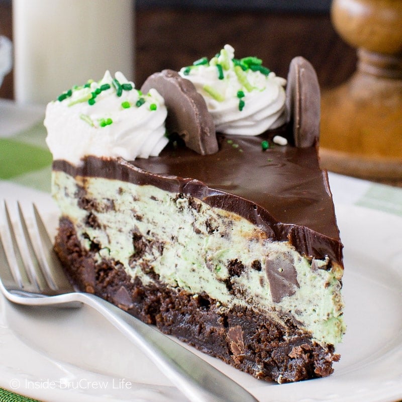 A slice of mint cheesecake with a brownie crust.