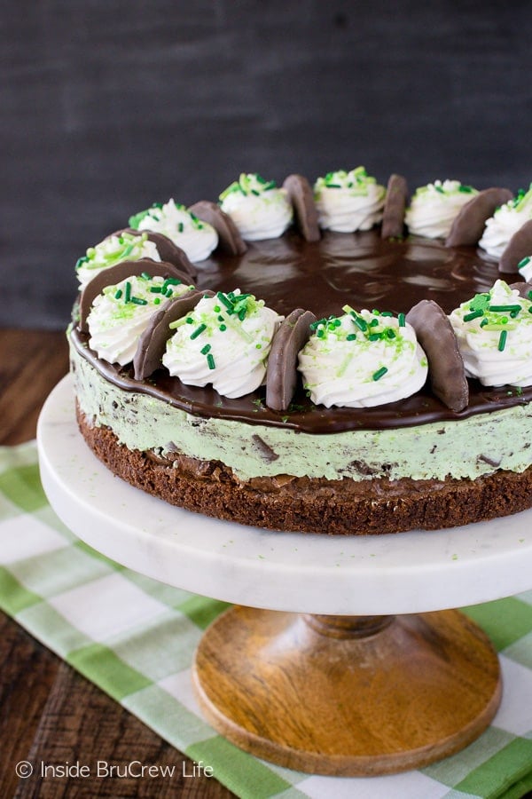 A white cake plate with a full size thin mint cheesecake on it.