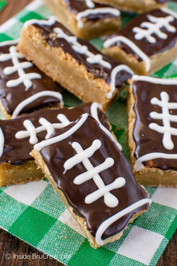 Cookie bars decorated like footballs scattered on a white and green towel