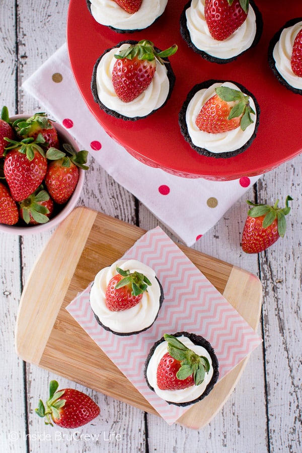 An overhead picture of small chocolate tarts with cool whip and a strawberry on top.