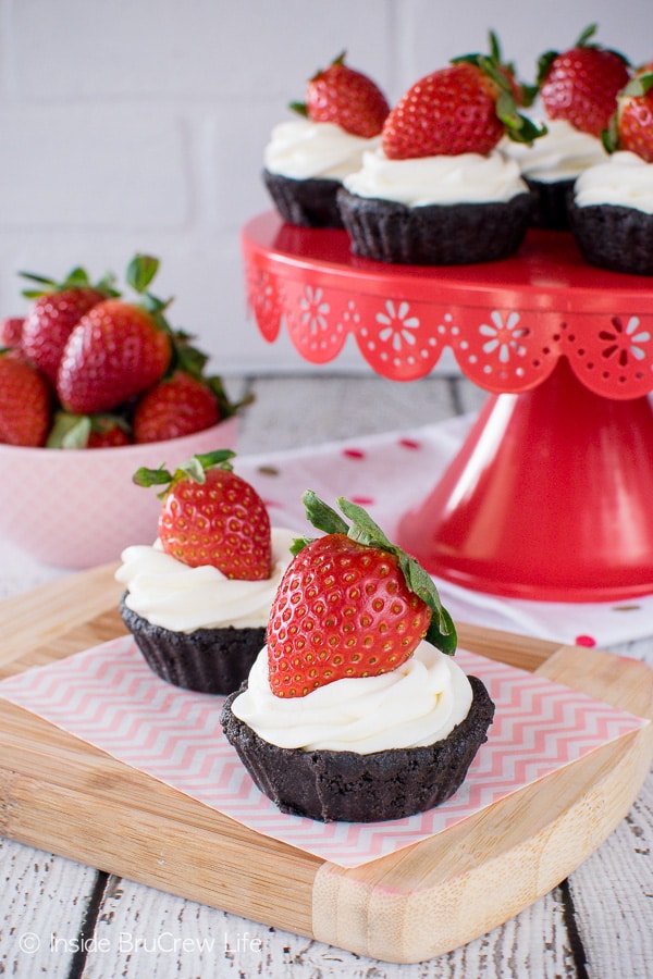 A small chocolate tart with cool whip and a strawberry on top.