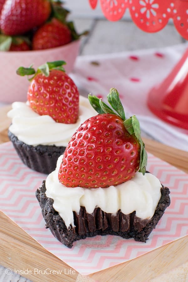 A small chocolate tart with cool whip and a strawberry on top.