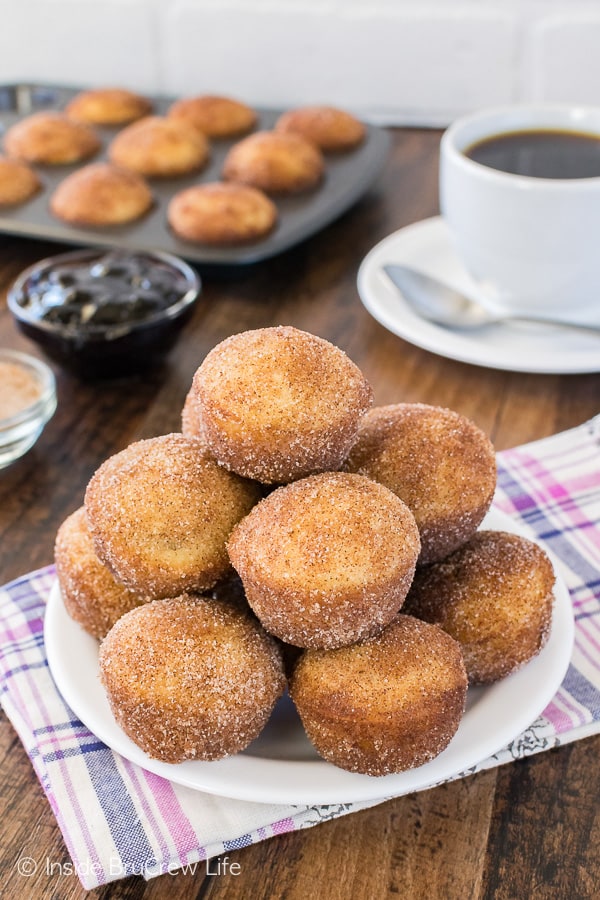 A pile of Blueberry Jelly Donut Holes on a white plate with coffee in the background