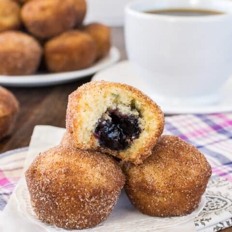 Three blueberry jelly donut holes on a white doily