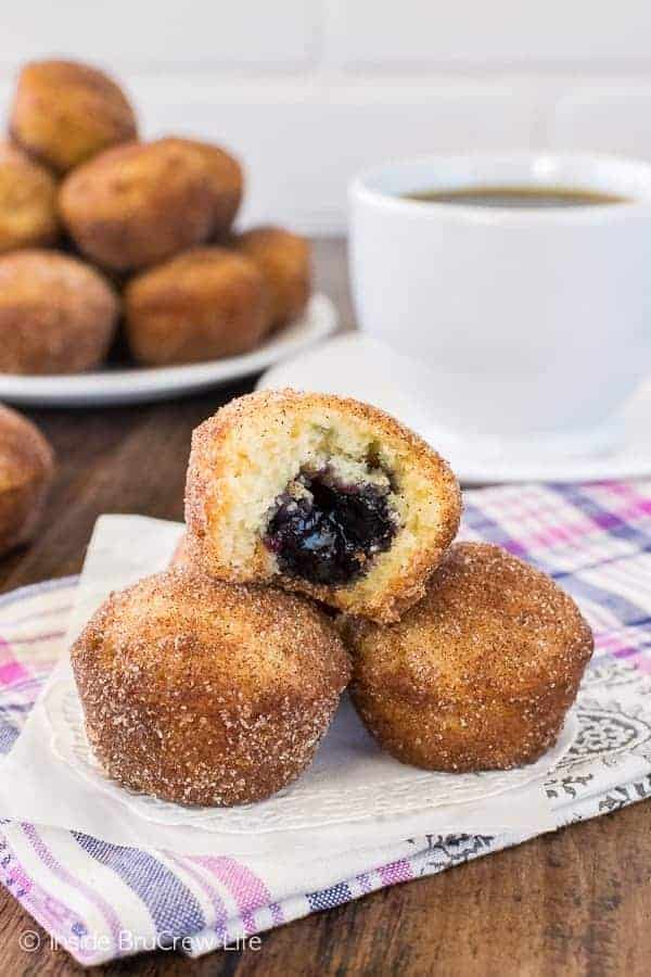 A stack of blueberry jelly donut holes with a bite out of one on a white doily