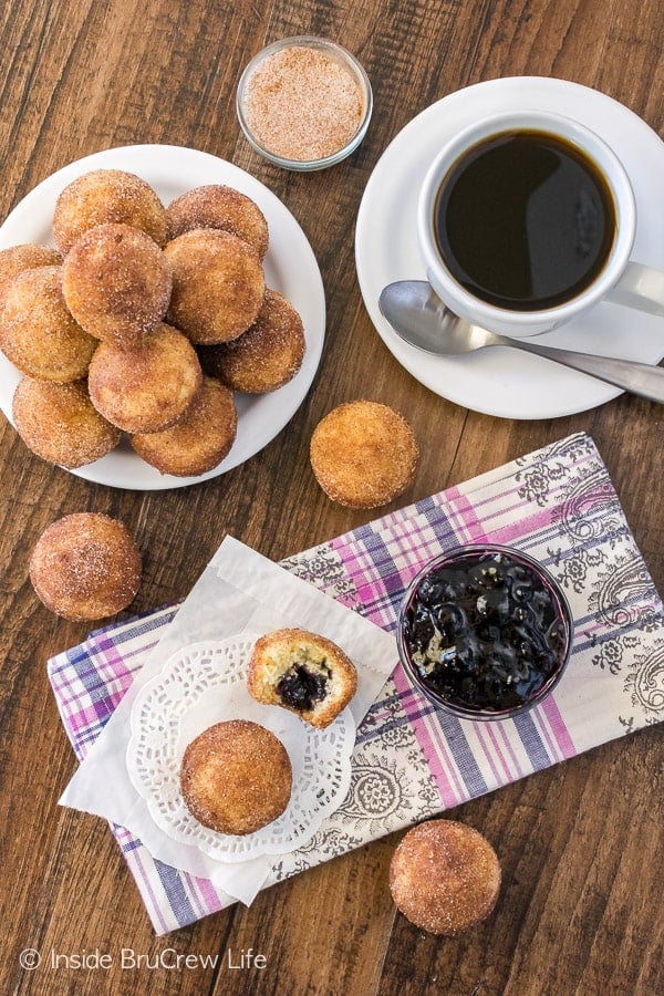 Overhead picture of blueberry jelly donut holes on white plates and white doiles