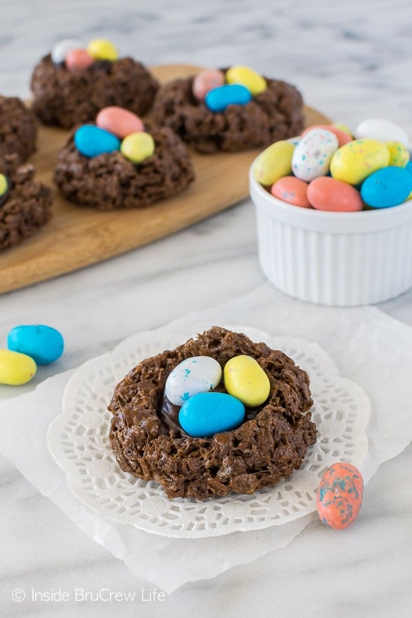 Chocolate bird nests with 3 malt chocolate eggs in them on a white doily.