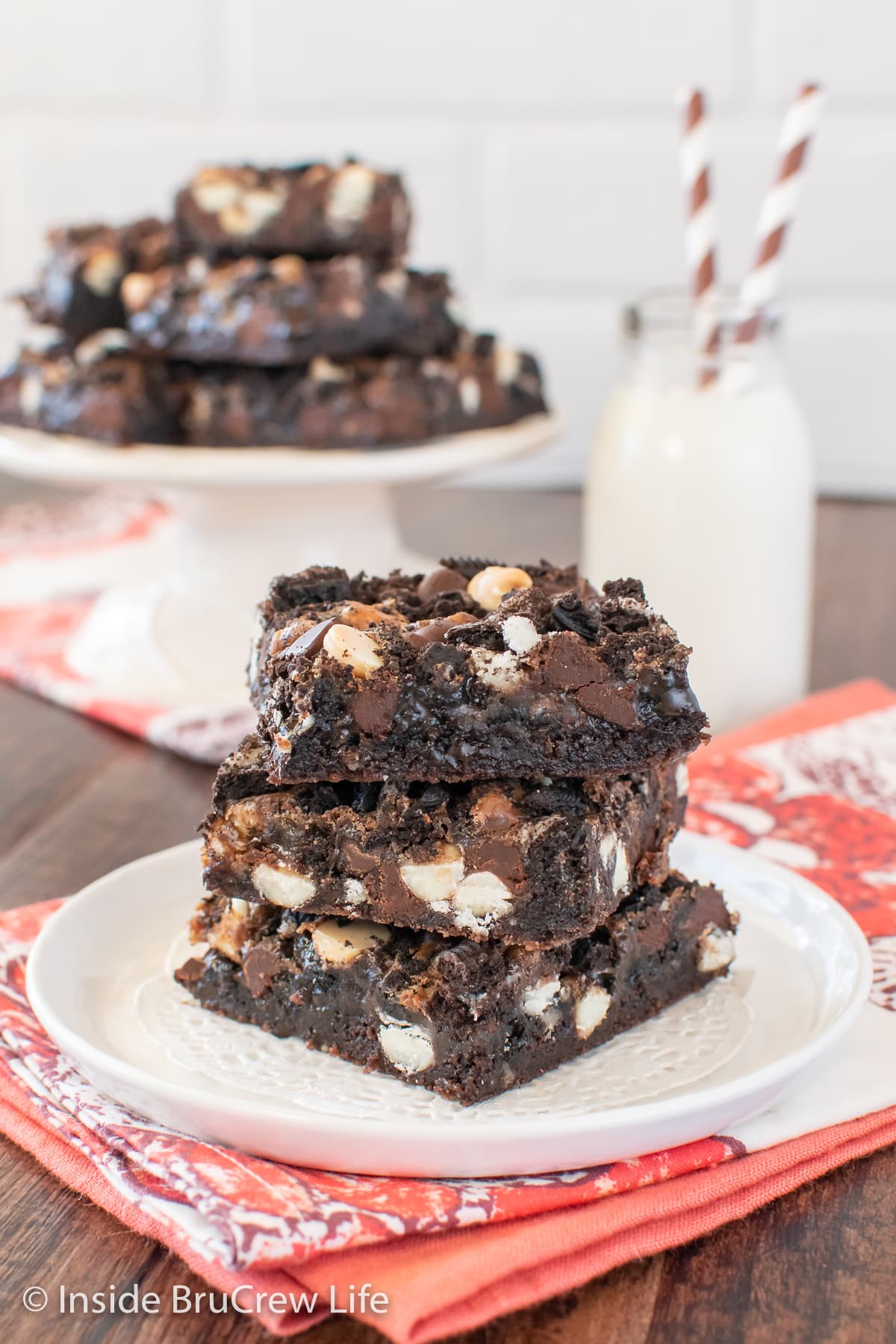 Three chocolate brownie bars stacked on a white plate.