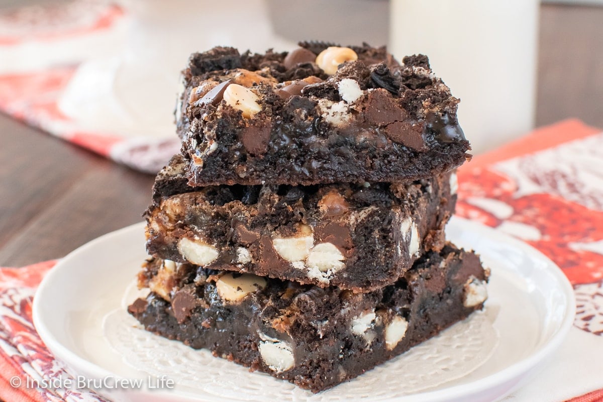 Three chocolate brownie bars stacked on a white plate.