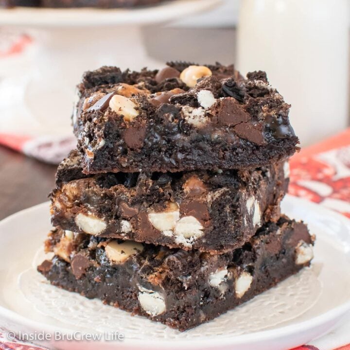 Three chocolate brownie bars stacked on a white plate.