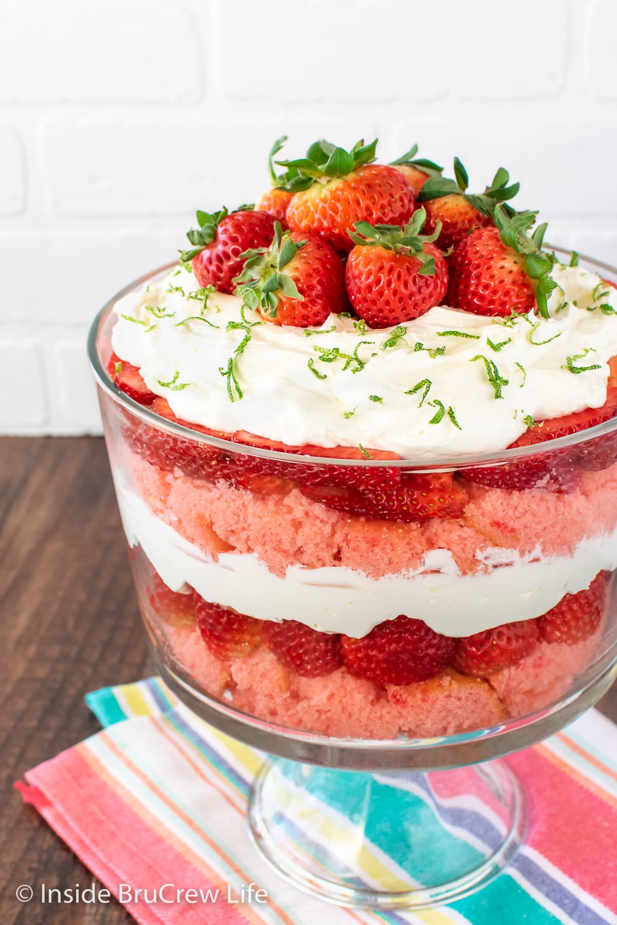 A clear bowl filled with cake, cheesecake, and berries.