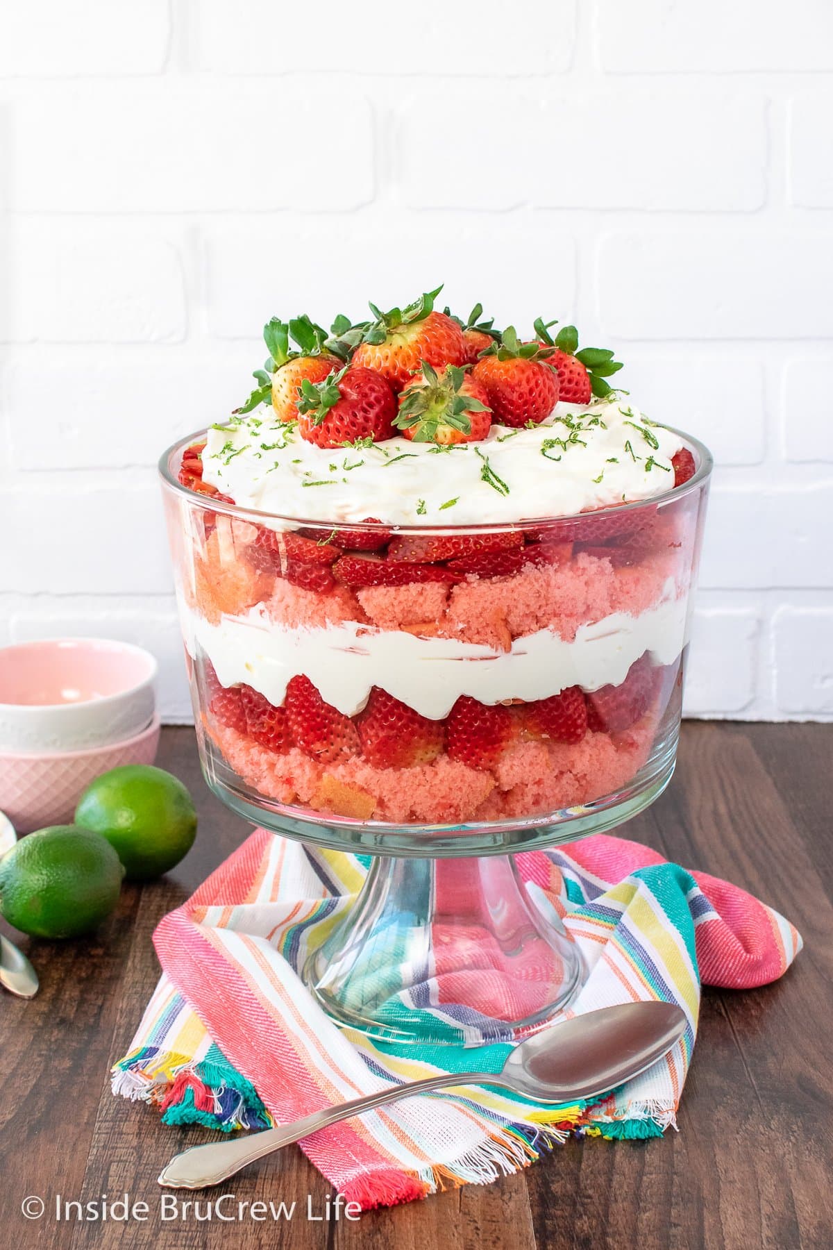 A clear bowl filled with cake cubes, filling, and berries.