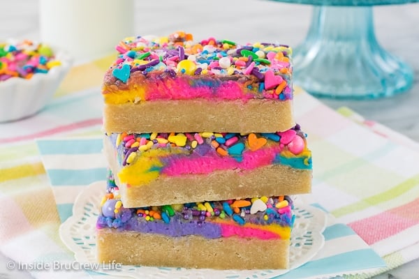 Three frosted unicorn sugar cookie bars stacked on top of each other on a colorful towel